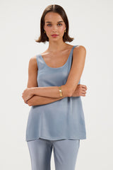 A woman modeling a light blue sleeveless tank top and matching light blue pants against a plain light gray studio background.